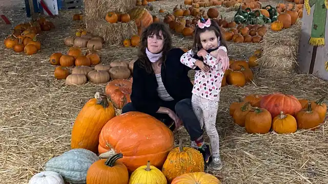 A family posing together among a colorful pumpkin display
