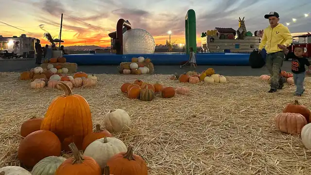 Farm attractions and pumpkins beneath a glowing sunset sky