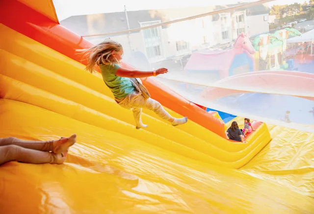 A child enjoying a bright orange and yellow giant slide